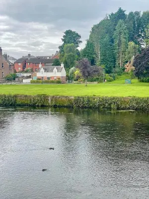 a body of water with a house in the background at Relax by the River, at Millgreen House in Dumfries