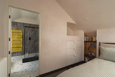 an attic bedroom with a bed and a mirror at Swallow Barn at Greenclose Farm in Penrith