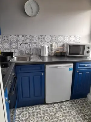 a kitchen with blue cabinets and a sink and a clock at Studio No5, Cockermouth The Lakes in Cockermouth