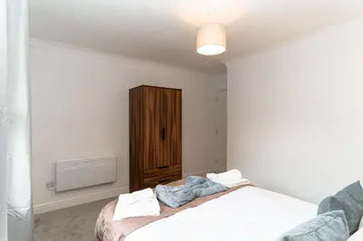 a bedroom with a bed and a wooden cabinet at Lovely 1 Bed Harbour-side Apartment - Sea Views in Whitehaven