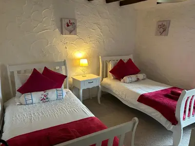 a bedroom with two beds with red pillows at Oronsay, 2 Weint End Cottages, Great Urswick, Ulverston Cumbria LA120SP in Moffat