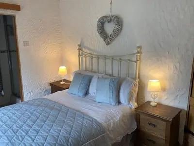 a bedroom with a bed with a heart on the wall at Oronsay, 2 Weint End Cottages, Great Urswick, Ulverston Cumbria LA120SP in Moffat