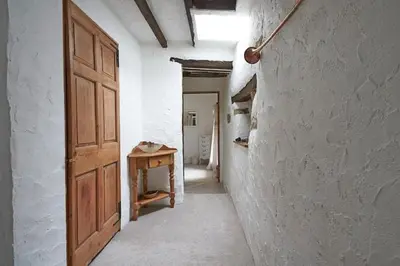 an empty hallway with a wooden door and a table at Oronsay, 2 Weint End Cottages, Great Urswick, Ulverston Cumbria LA120SP in Moffat