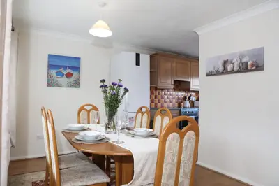 a dining room with a table and chairs and a kitchen at 70 Abbotsbury Road, Bury St Edmunds, IP33 2HP in Moffat