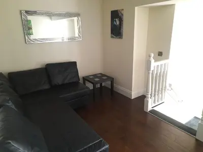 a living room with a black couch and a table at Kirkcudbright Holiday Apartments - Apartment B in Kirkcudbright