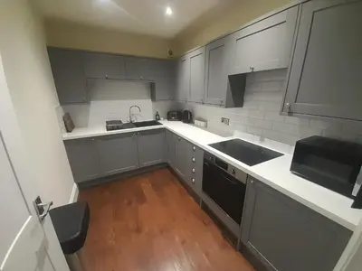 a kitchen with gray cabinets and a wooden floor at Kirkcudbright Holiday Apartments - Apartment B in Kirkcudbright