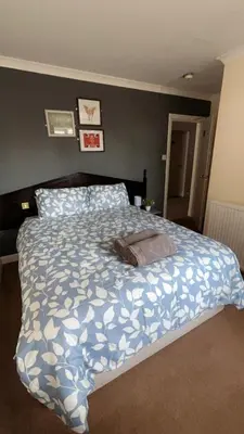 a bedroom with a bed with a blue and white comforter at QueensBerry Annan in Annan
