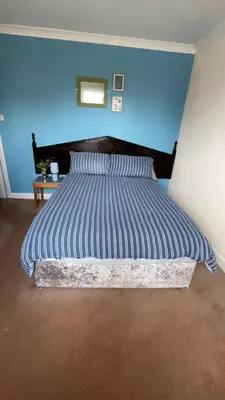 a bed in a bedroom with a blue wall at QueensBerry Annan in Annan