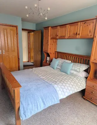 a bedroom with a large bed with wooden cabinets at The Yard Bungalow in Sanquhar