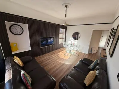 a living room with a couch and a clock on the wall at 3 bedroom traditional apartment in Ayr