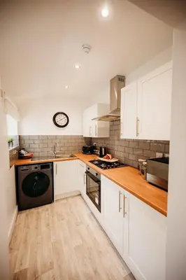 a kitchen with white cabinets and a clock on the wall at 4 Bed Sheffield home in Moffat