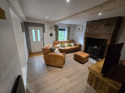 a living room with a couch and a fireplace at Lakes Cottage Beckermet in Beckermet
