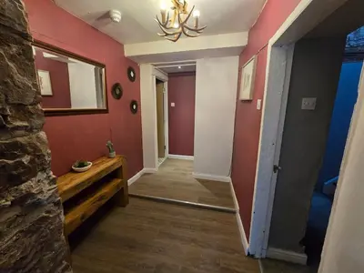 a hallway with red walls and a chandelier at Lakes Cottage Beckermet in Beckermet