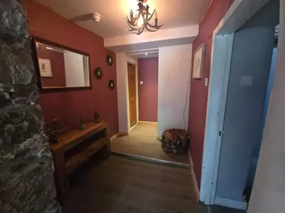 a hallway with red walls and a chandelier at Lakes Cottage Beckermet in Beckermet