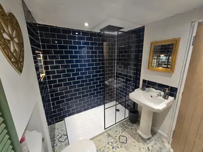 a bathroom with a sink and a shower with blue tiles at Lakes Cottage Beckermet in Beckermet