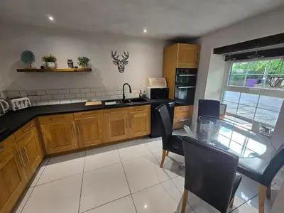 a kitchen with a sink and a table with chairs at Lakes Cottage Beckermet in Beckermet