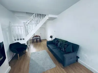 a living room with a green couch and a staircase at Holly Terrace - 2 Bedrooms - Sleeps 3 in Whitehaven