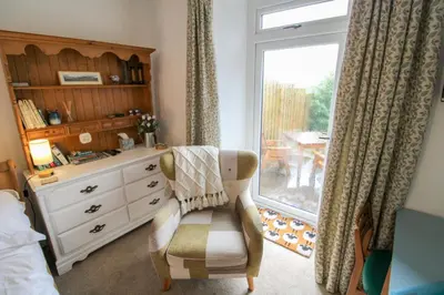 a bedroom with a dresser and a chair and a window at Lorton View, nestles on the fellside with walks from the door close to Lorton in Lorton