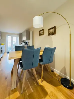a dining room table with chairs and a floor lamp at Stylish Two-Bedroom Flat with Garden Near Henley Town Centre in Moffat