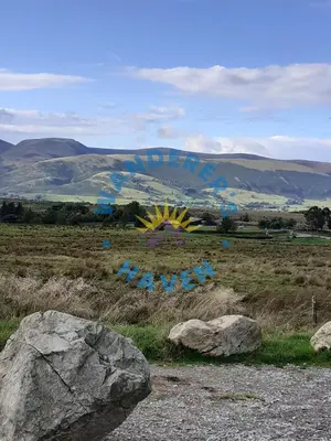 a field with some rocks and a painting on it at Wanderers Haven, Brigham, Cockermouth, Cumbria in Brigham