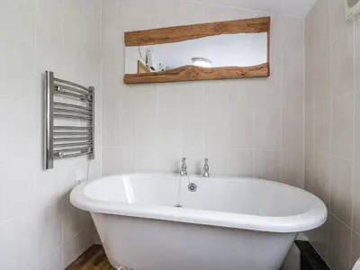 a white bath tub in a bathroom with a mirror at Daisy Cottage in Wigton