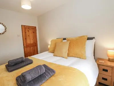 a bedroom with a bed with two towels on it at Daisy Cottage in Wigton