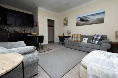 a living room with a couch and a kitchen at Troon - Coastal Getaway in Troon