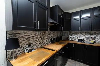 a kitchen with black cabinets and a wooden counter top at Troon - Coastal Getaway in Troon