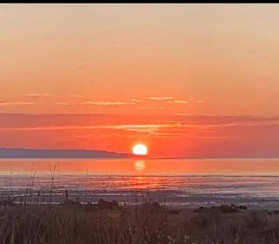 a sunset over the ocean with the sun setting at The Beach House in Moffat