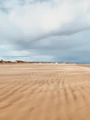 an empty beach with a cloudy sky in the background at The Beach House in Moffat