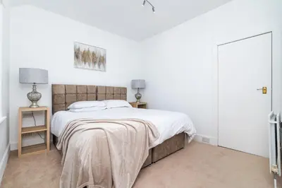 a bedroom with a large bed with white walls at 2Bedroom House - Free Parking- by Holiday Homes in Annan
