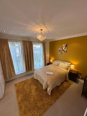 a bedroom with a large bed and a chandelier at Fairholme Gardens House in Moffat