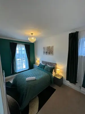a bedroom with a green bed and two windows at Fairholme Gardens House in Moffat