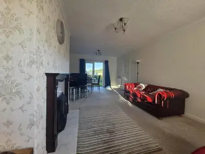 a living room with a red couch and a table at Lovely 3 Bedroom House 5 Minutes M6 or Carlisle in Carlisle