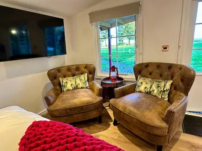 a bedroom with two chairs and a bed and a table at Stylish Cabin with Countryside Views and King Bed in Maybole