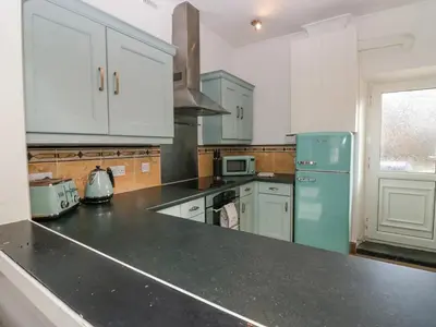 a kitchen with white cabinets and a blue refrigerator at Cosy Cottage in Cumbria, West of Lake District in Broughton Moor
