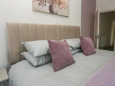 a bed with three purple pillows on top of it at Cosy Cottage in Cumbria, West of Lake District in Broughton Moor