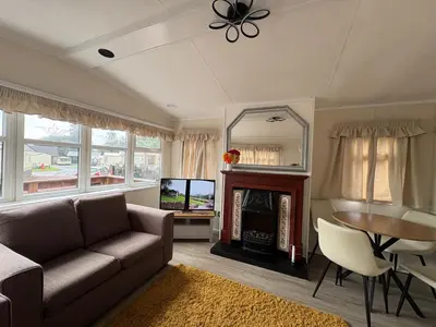 a living room with a couch and a table and a television at Cosy Caravan by the sea in Cairnryan
