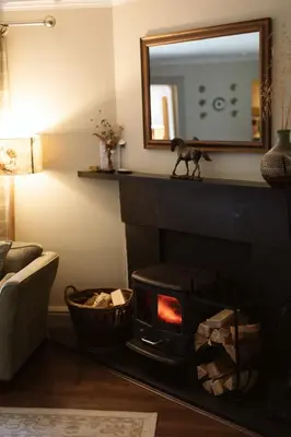 a living room with a fireplace and a mirror at The Coach House in Castle Douglas