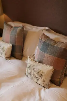 a bed with two pillows and a plaid pillow at The Coach House in Castle Douglas