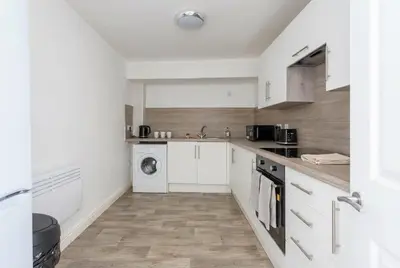 a kitchen with white cabinets and a washer and dryer at Fabulous 1 Bed Harbour-side Apartment with Balcony in Whitehaven