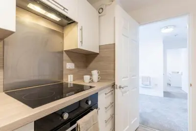 a kitchen with white cabinets and a stove top oven at Fabulous 1 Bed Harbour-side Apartment with Balcony in Whitehaven