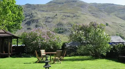 a table and chairs on a lawn with a mountain at School House in Patterdale