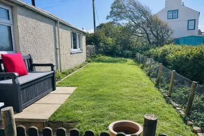 a garden with a bench on a lawn at Old Post Office By The Sea in Allonby