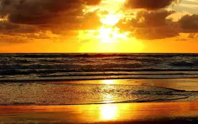 a sunset on a beach with the ocean at Old Post Office By The Sea in Allonby