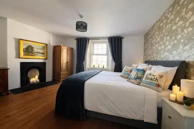 a bedroom with a large bed and a fireplace at Old Post Office By The Sea in Allonby