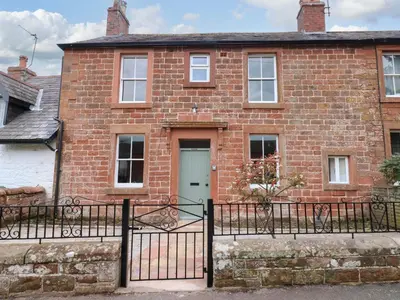 an old brick house with a gate and a door at Milford in Carlisle