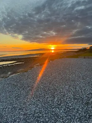 a sunset on a rocky beach with the sun setting at Rumblekirn in Annan