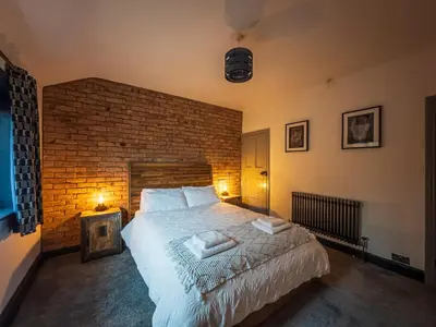 a bedroom with a large bed and a brick wall at Coastal Lakes Mews Cottage