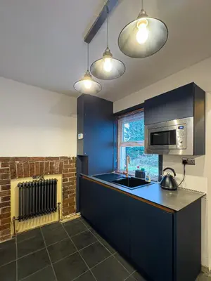 a kitchen with blue cabinets and a sink and a microwave at Coastal Lakes Mews Cottage